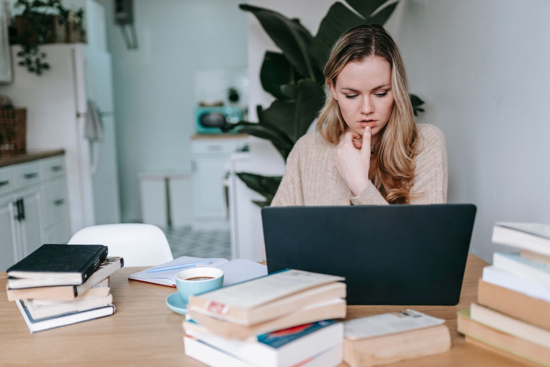An adult learner studying with a laptop, books and a notebook