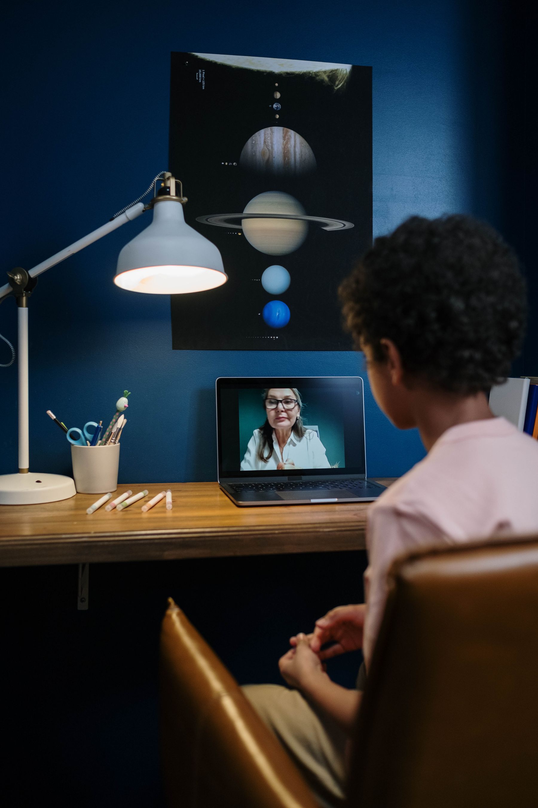 A child engaged in a live online lesson at a home study desk